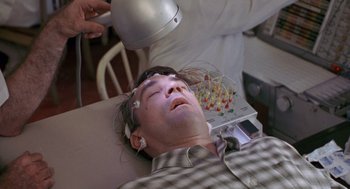 Movie still from “Awakenings” (1990), directed by Penny Marshall – A man is getting his head examined by an electroencephalologist; Close Up shot, High angle