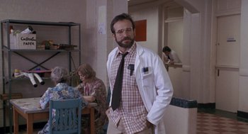 Movie still from “Awakenings” (1990), directed by Penny Marshall – A man with a beard and glasses in a white lab coat; Medium shot, Over the shoulder angle