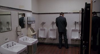 Movie still from “Awakenings” (1990), directed by Penny Marshall – A man standing in a bathroom next to urinals; Wide shot, High angle