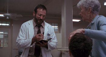 Movie still from “Awakenings” (1990), directed by Penny Marshall – A man in a white lab coat writing on a notepad; Medium shot, Low angle