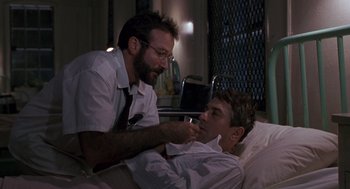 Movie still from “Awakenings” (1990), directed by Penny Marshall – A man in a hospital bed talking to another man; Medium shot, Over the shoulder angle