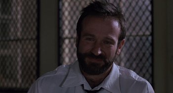 Movie still from “Awakenings” (1990), directed by Penny Marshall – A man with a goatee is smiling for the camera; Close Up shot, Over the shoulder angle