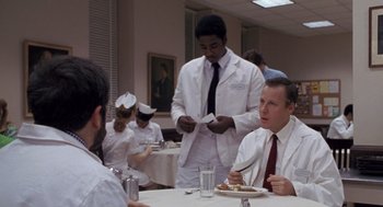 Movie still from “Awakenings” (1990), directed by Penny Marshall – A group of people sitting at a table eating food; Medium shot, Over the shoulder angle