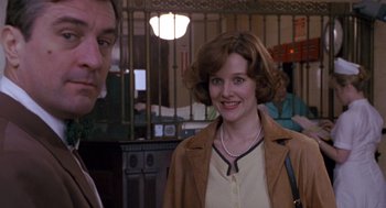 Movie still from “Awakenings” (1990), directed by Penny Marshall – A woman in a brown jacket standing next to a man in a brown jacket; Medium shot, Over the shoulder angle