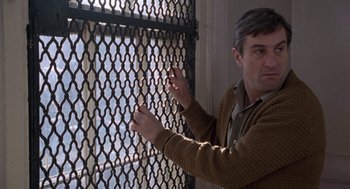 Movie still from “Awakenings” (1990), directed by Penny Marshall – A man in a brown jacket is looking through a fence; Medium shot, Low angle
