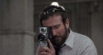 Movie still from “Awakenings” (1990), directed by Penny Marshall – A man with a beard holding a vintage camera; Close Up shot, Low angle