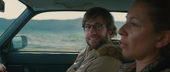 Movie still from “Away We Go” (2009), directed by Sam Mendes – A man with glasses and a beard sitting in the back of a car; Close Up shot, Over the shoulder angle