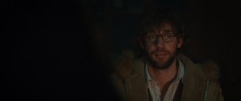 Movie still from “Away We Go” (2009), directed by Sam Mendes – A man with a beard and glasses in a dark room; Close Up shot, Over the shoulder angle