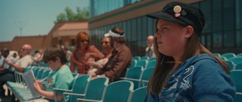 Movie still from “Away We Go” (2009), directed by Sam Mendes – A group of people sitting in a row of chairs; Close Up shot, Over the shoulder angle