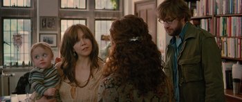 Movie still from “Away We Go” (2009), directed by Sam Mendes – A group of people standing in a room talking to each other; Medium shot, Over the shoulder angle