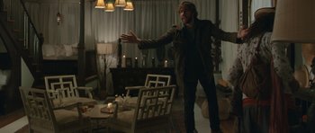 Movie still from “Away We Go” (2009), directed by Sam Mendes – A man standing in a living room in front of candles; Wide shot, Over the shoulder angle
