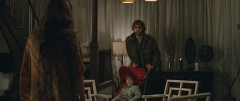 Movie still from “Away We Go” (2009), directed by Sam Mendes – A man standing next to a woman sitting in a chair in a room; Medium shot, Over the shoulder angle