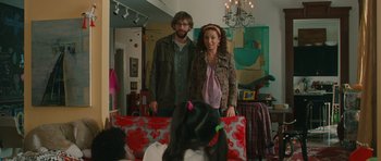 Movie still from “Away We Go” (2009), directed by Sam Mendes – A man and a woman posing for a picture on a couch; Medium shot, Over the shoulder angle