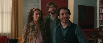 Movie still from “Away We Go” (2009), directed by Sam Mendes – A group of people standing next to each other in a room; Medium shot, Over the shoulder angle
