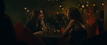 Movie still from “Away We Go” (2009), directed by Sam Mendes – Two women are sitting at a table with drinks in front of them; Medium shot, Over the shoulder angle