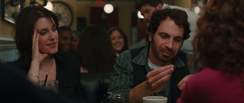 Movie still from “Away We Go” (2009), directed by Sam Mendes – A man sitting in front of a group of people; Medium shot, Over the shoulder angle