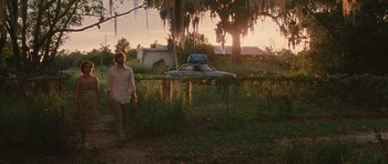 Movie still from “Away We Go” (2009), directed by Sam Mendes – A man standing in front of an abandoned car; Wide shot, Over the shoulder angle