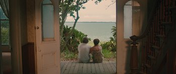 Two people sitting on a porch looking out at the water