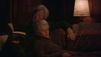 Movie still from “Away from Her” (2006), directed by Sarah Polley – An older man and woman are sleeping on a couch; Medium shot, High angle