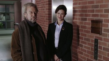 Movie still from “Away from Her” (2006), directed by Sarah Polley – A man and a woman standing next to each other in front of a brick wall; Medium shot, Low angle
