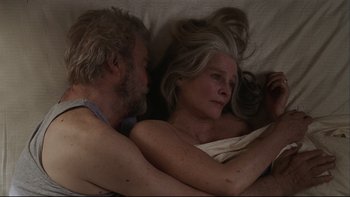 Movie still from “Away from Her” (2006), directed by Sarah Polley – An older man and a younger woman laying in a bed together; Close Up shot, Overhead angle