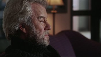 Movie still from “Away from Her” (2006), directed by Sarah Polley – An older man sitting on a couch with his head turned to the side; Close Up shot, Over the shoulder angle