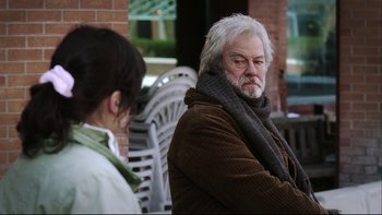 Movie still from “Away from Her” (2006), directed by Sarah Polley – An older man and a younger woman sitting at a table; Medium shot, Over the shoulder angle