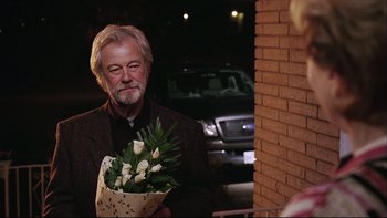 Movie still from “Away from Her” (2006), directed by Sarah Polley – An older man holding a bouquet of flowers; Medium shot, Over the shoulder angle