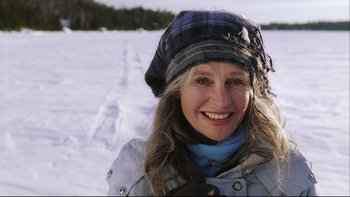 Movie still from “Away from Her” (2006), directed by Sarah Polley – A woman in a plaid hat smiles for the camera; Close Up shot, High angle