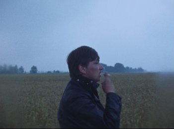 Movie still from “Baal” (1970), directed by Volker Schlöndorff – A man standing in front of a field with trees in the background; Medium shot, High angle