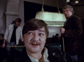 Movie still from “Baal” (1970), directed by Volker Schlöndorff – A man with a mustache is smiling for the camera; Close Up shot, Low angle