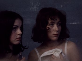 Movie still from “Baal” (1970), directed by Volker Schlöndorff – Two young women standing next to each other in a dark room; Close Up shot, High angle