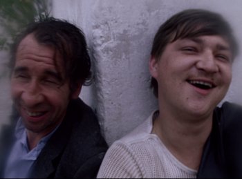 Movie still from “Baal” (1970), directed by Volker Schlöndorff – Two men sitting next to each other and laughing; Close Up shot, Low angle