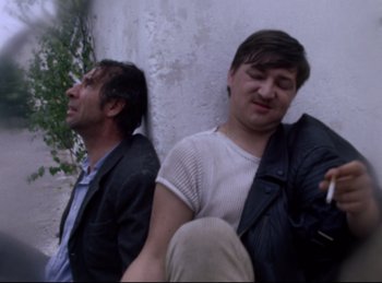 Movie still from “Baal” (1970), directed by Volker Schlöndorff – Two men sitting next to each other on the ground; Medium shot, Low angle
