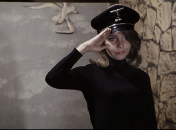 Movie still from “Baal” (1970), directed by Volker Schlöndorff – A woman saluting while wearing a black hat; Medium shot, Low angle