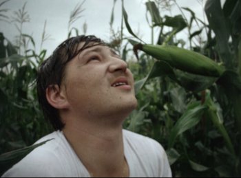 Movie still from “Baal” (1970), directed by Volker Schlöndorff – A man in white shirt looking up at a green plant; Close Up shot, Low angle