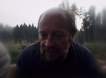 Movie still from “Baal” (1970), directed by Volker Schlöndorff – A man with a goatee and a beard is in the woods; Close Up shot, Low angle