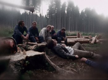 Movie still from “Baal” (1970), directed by Volker Schlöndorff – A group of people sitting on logs in the woods; Wide shot, High angle