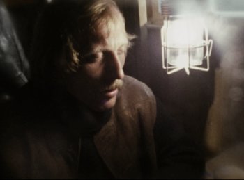 Movie still from “Baal” (1970), directed by Volker Schlöndorff – A man with long hair and a mustache is looking at the camera; Close Up shot, Over the shoulder angle