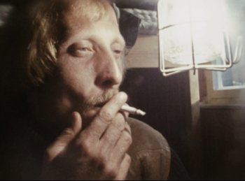 Movie still from “Baal” (1970), directed by Volker Schlöndorff – A man smoking a cigarette while sitting in a chair; Close Up shot, Low angle