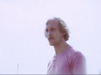 Movie still from “Baal” (1970), directed by Volker Schlöndorff – A man in a pink shirt is looking at the camera; Close Up shot, Low angle