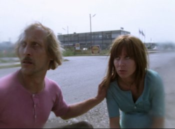 Movie still from “Baal” (1970), directed by Volker Schlöndorff – A man and a woman standing next to each other on the side of the road; Medium shot, Low angle