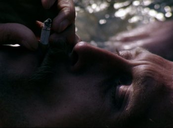 Movie still from “Baal” (1970), directed by Volker Schlöndorff – A man smoking a cigarette while laying down; Extreme Close Up shot, Overhead angle