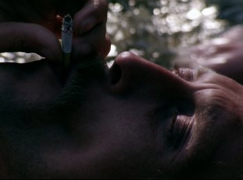 Movie still from “Baal” (1970), directed by Volker Schlöndorff – A person smoking a cigarette while laying down; Extreme Close Up shot, Overhead angle
