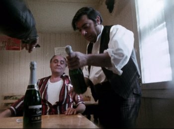 Movie still from “Baal” (1970), directed by Volker Schlöndorff – A man pouring champagne into a bottle; Medium shot, Low angle