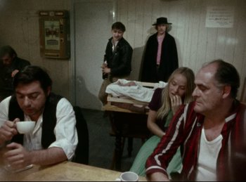 Movie still from “Baal” (1970), directed by Volker Schlöndorff – A group of people sitting around a table; Wide shot, Over the shoulder angle