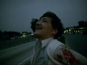 Movie still from “Baal” (1970), directed by Volker Schlöndorff – A man with blood on his arm is walking down the street; Medium shot, High angle
