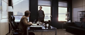 Movie still from “Stay” (2005), directed by Marc Forster – A man standing in front of another man at a desk; Wide shot, Over the shoulder angle