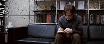 Movie still from “Stay” (2005), directed by Marc Forster – A man sitting on a couch writing in a notebook; Medium shot, High angle