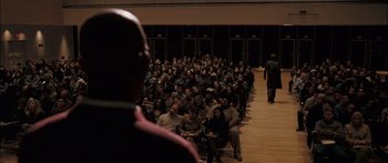 Movie still from “Stay” (2005), directed by Marc Forster – A large group of people sitting in front of a speaker; Extreme Wide shot, High angle